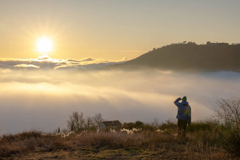 a man standing on top of a lush green hillside