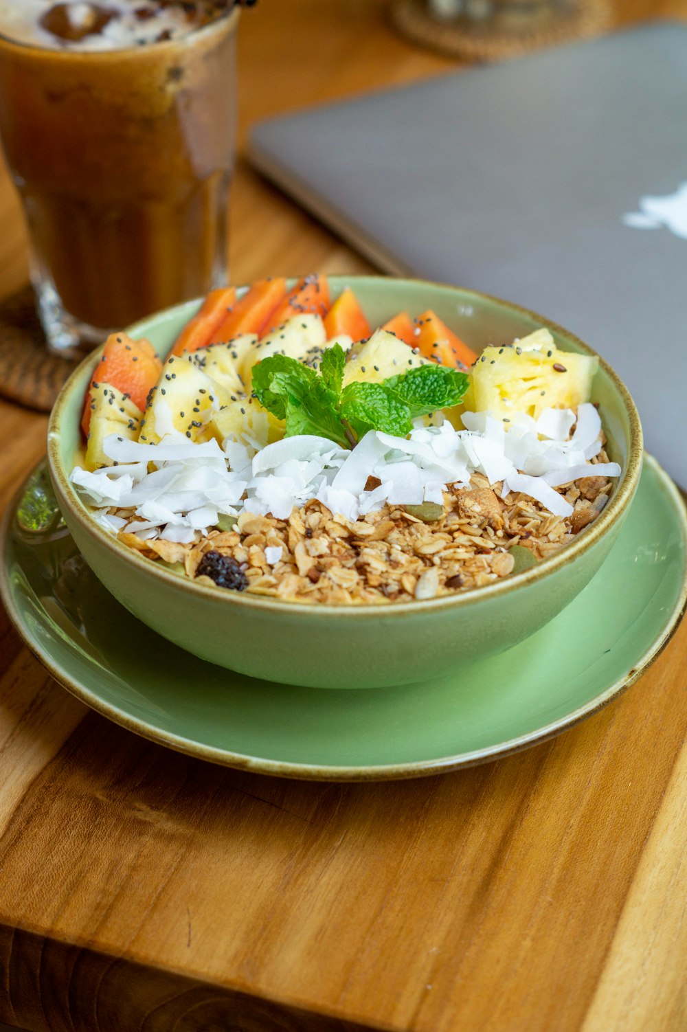 a bowl of food sitting on a table next to a laptop