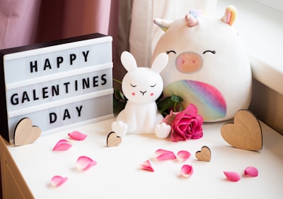 a white stuffed rabbit next to a sign that says happy valentine's day