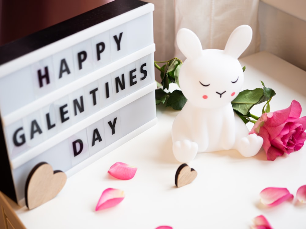 a white rabbit sitting on top of a table next to a sign