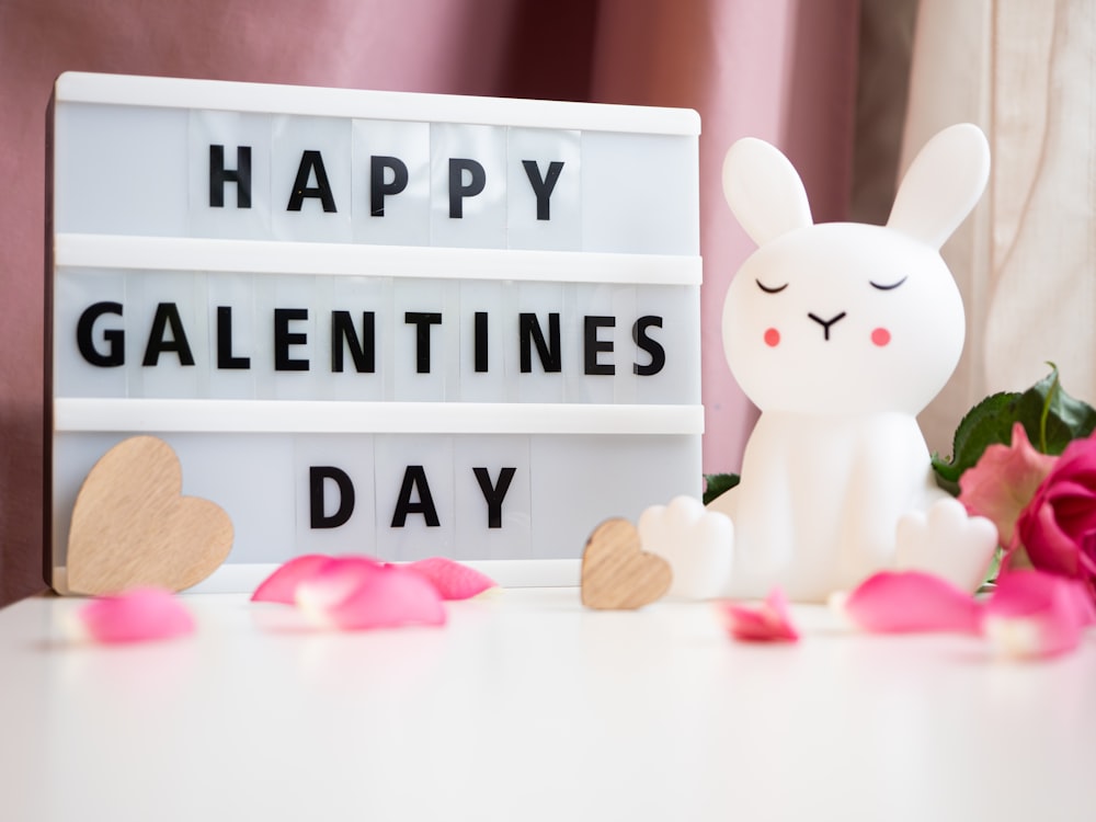 a sign that says happy valentine's day next to a pink rose