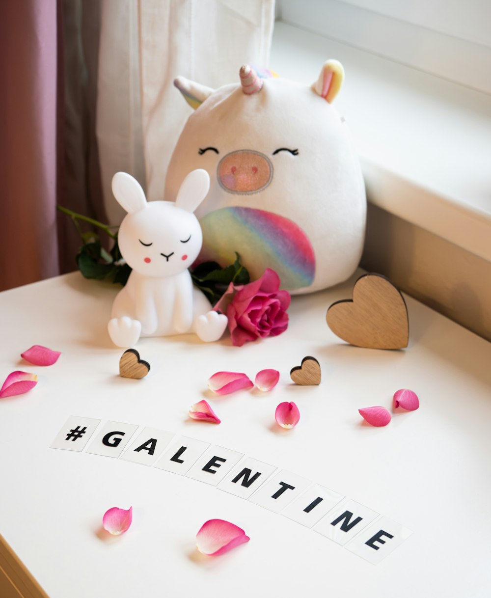 a white stuffed animal next to a pink rose