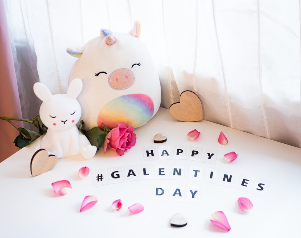 a white table topped with a stuffed animal next to a vase filled with flowers