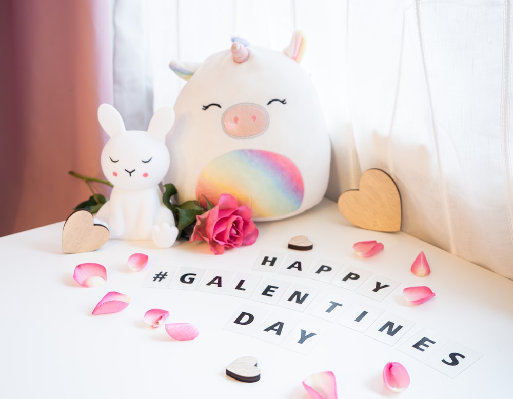 a white table topped with a stuffed animal and a pink rose