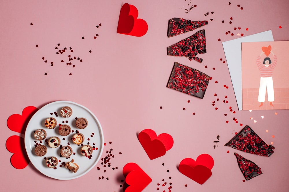 a plate of chocolates and a card on a pink background