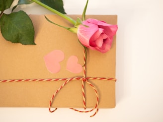 a pink rose sitting on top of a brown box