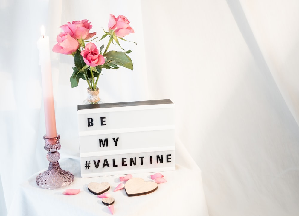 a vase of roses and a candle on a table