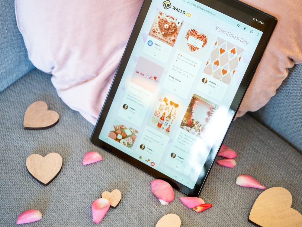 a tablet sitting on a couch with hearts scattered around it