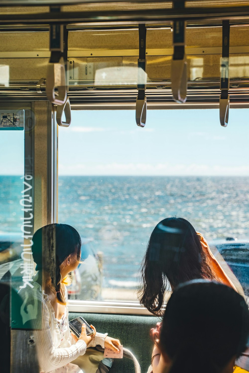 a woman sitting on a train next to the ocean