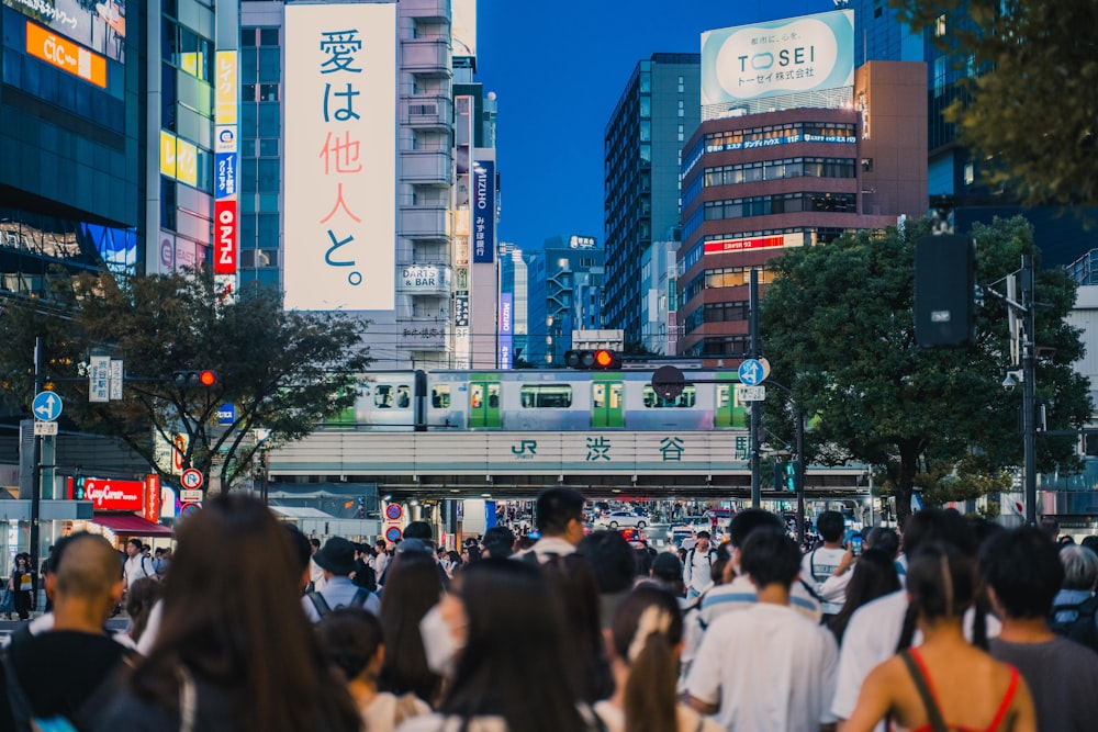 a crowd of people walking down a street next to tall buildings