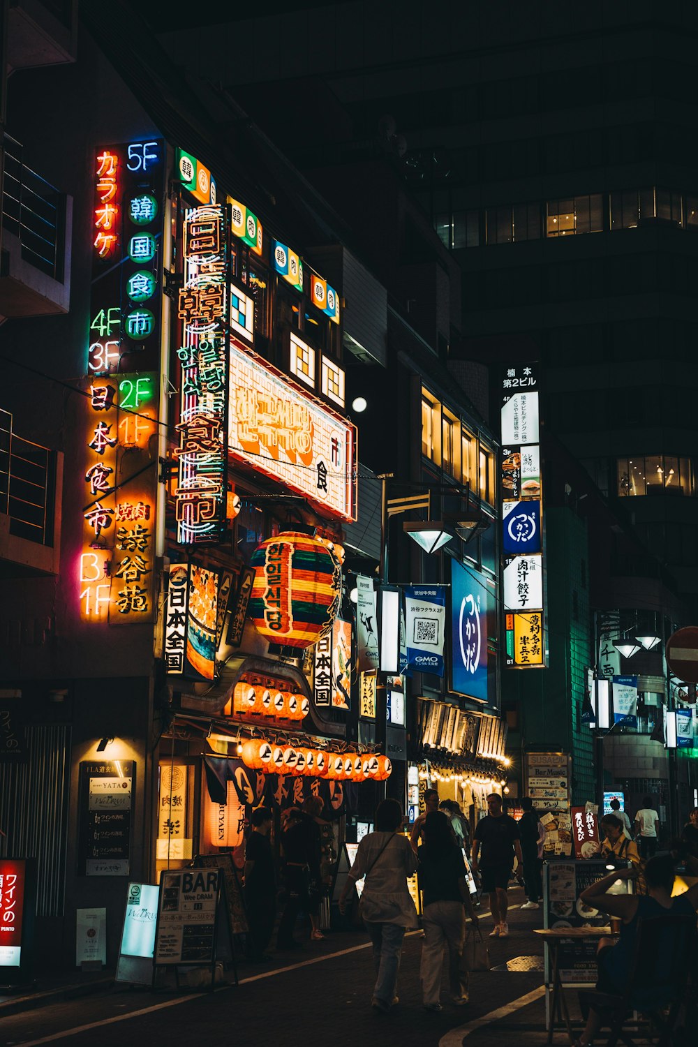 a group of people walking down a street at night