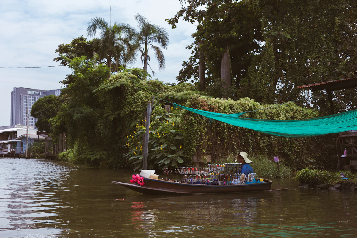A vendor selling goods from a small wooden boat on a Bangkok canal