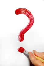 a hand holding a paintbrush and a red question mark