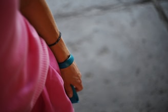 a woman in a pink dress holding onto a pair of blue bracelets
