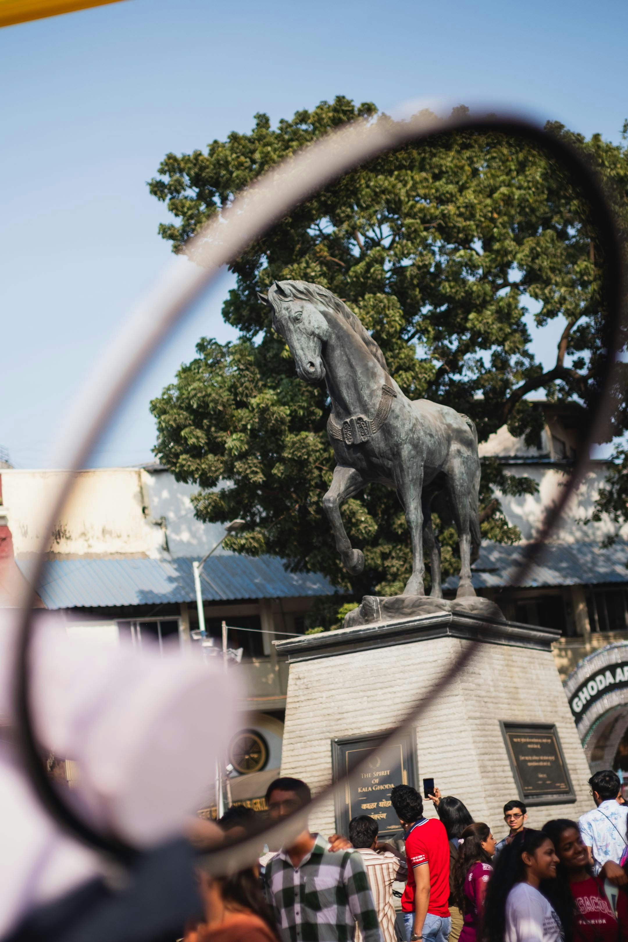 a crowd of people standing around a statue of a horse
