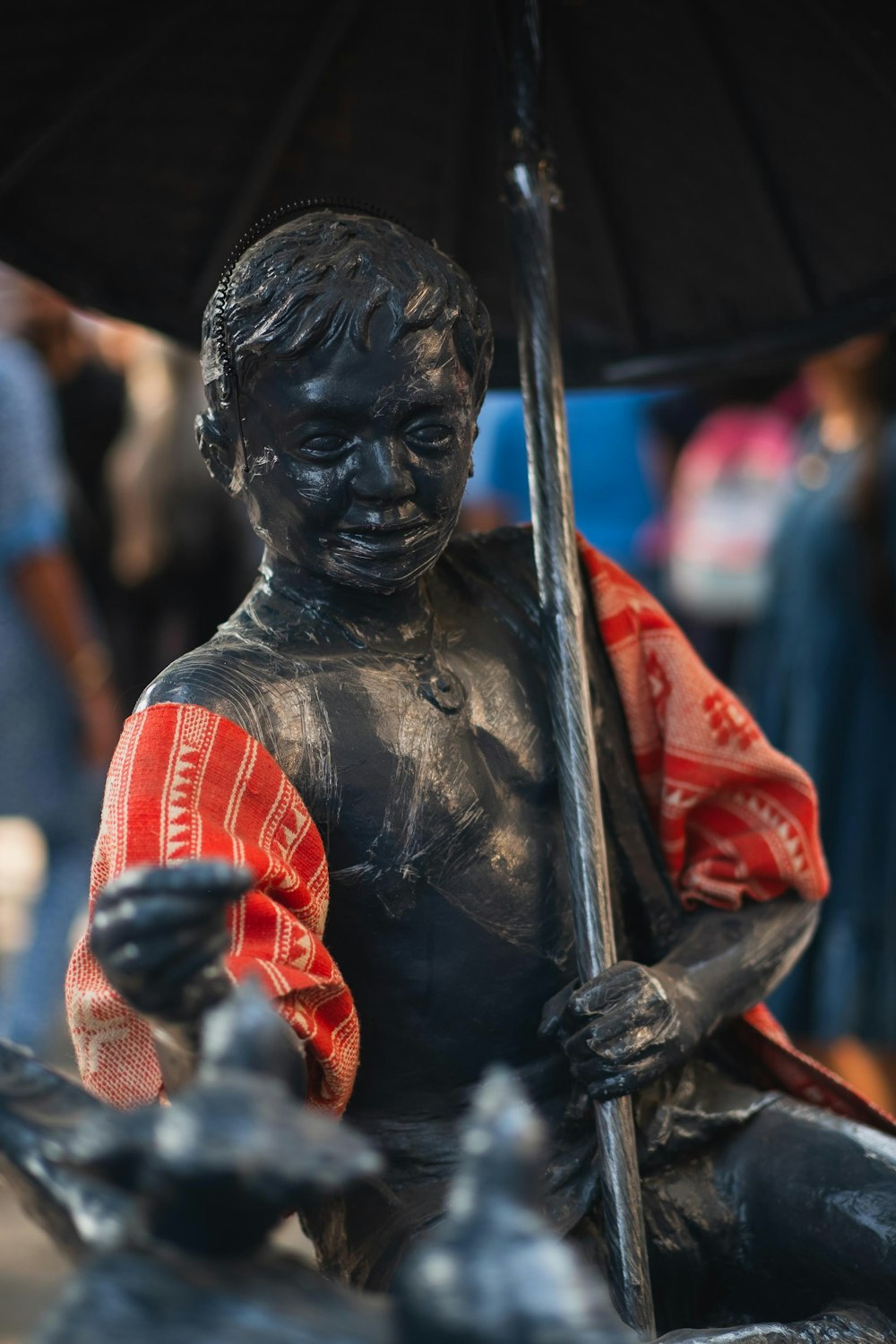 a statue of a man holding a black umbrella
