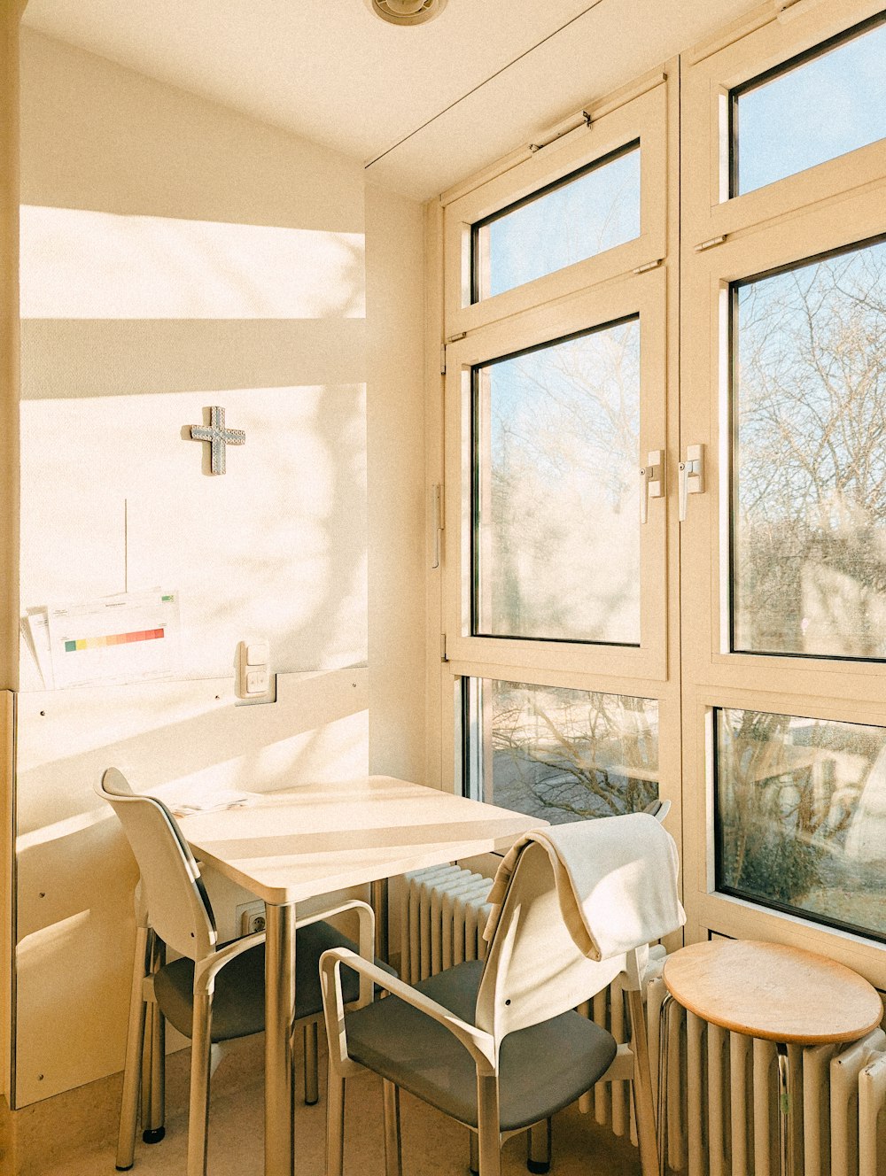 a room with a table, chairs, and a cross on the wall