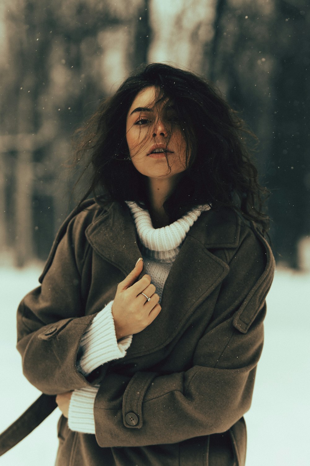 a woman standing in the snow with her arms crossed
