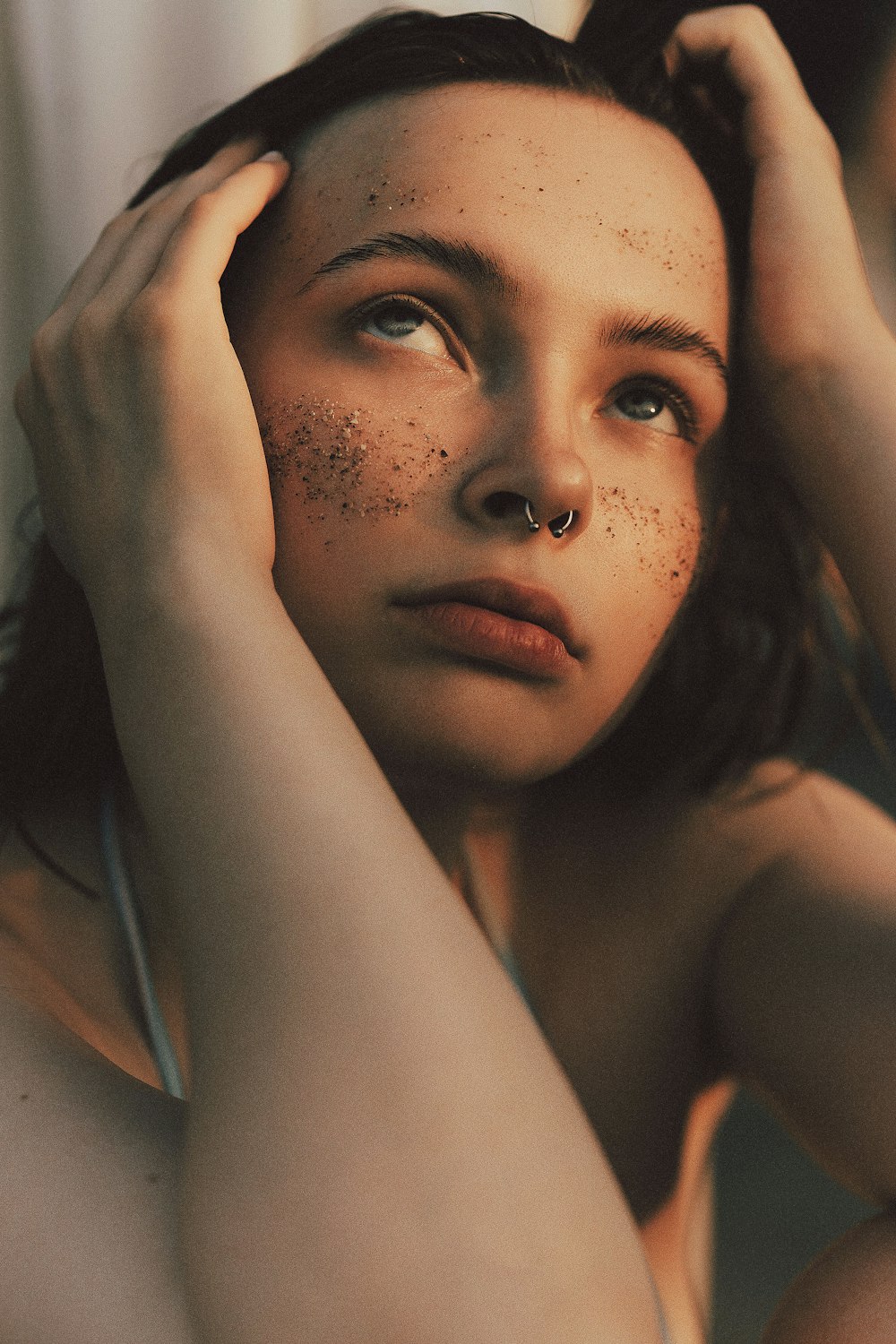 a woman with freckles on her face holding her hair