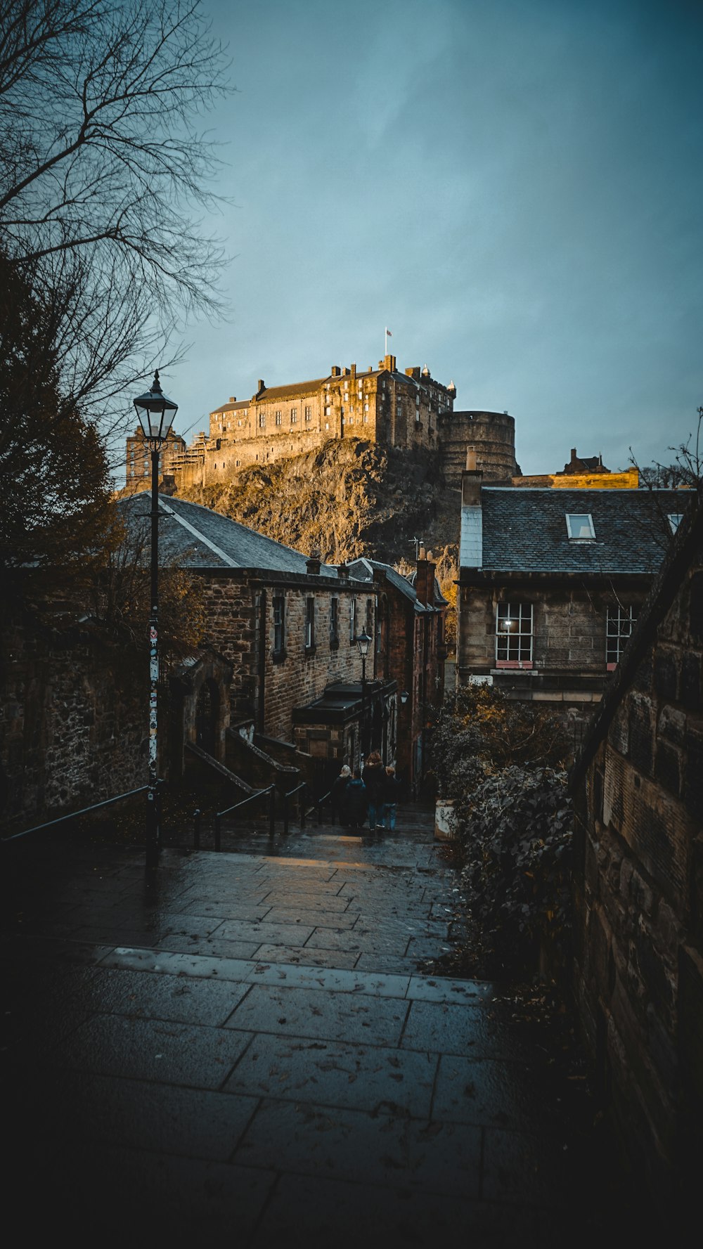 a stone building sitting on top of a hill next to a street light