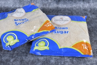 two bags of brown sugar sitting on top of a carpet
