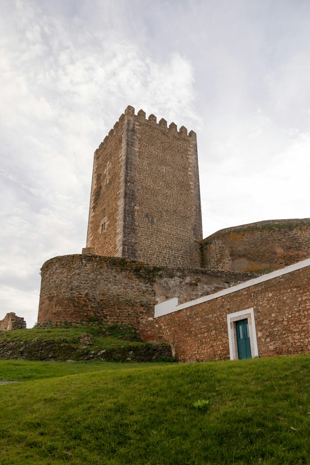 a tall brick building sitting on top of a lush green field