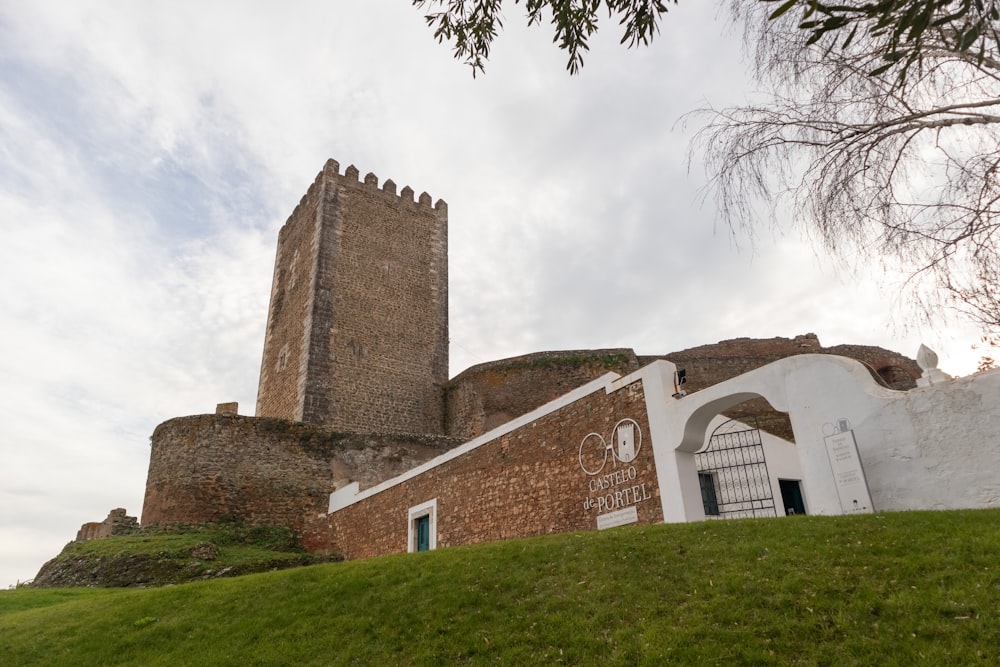 a castle with a tall tower sitting on top of a lush green hillside