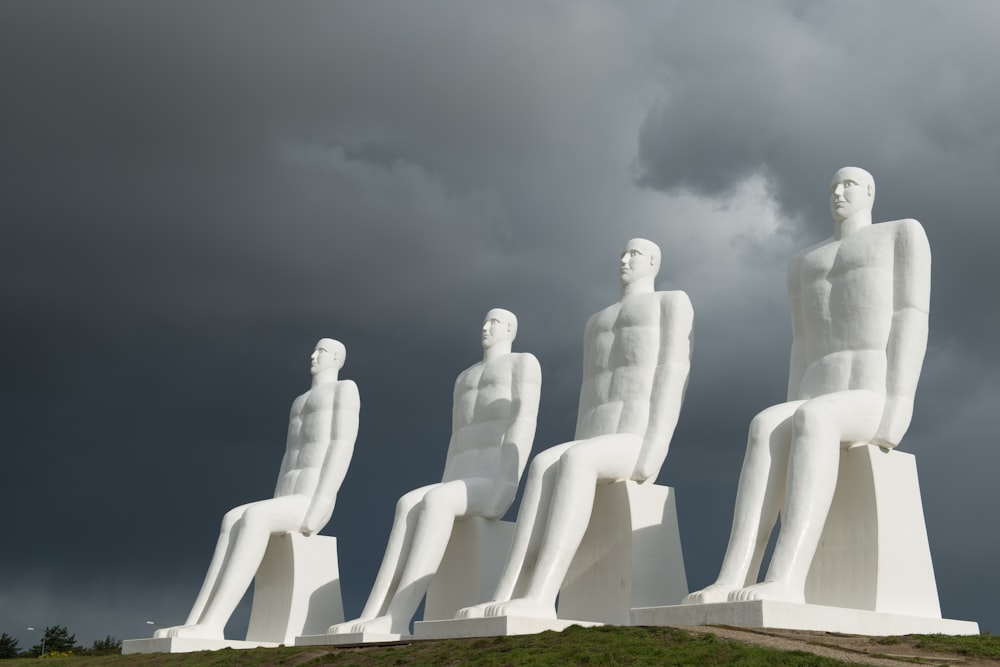 a group of white statues sitting on top of a lush green field