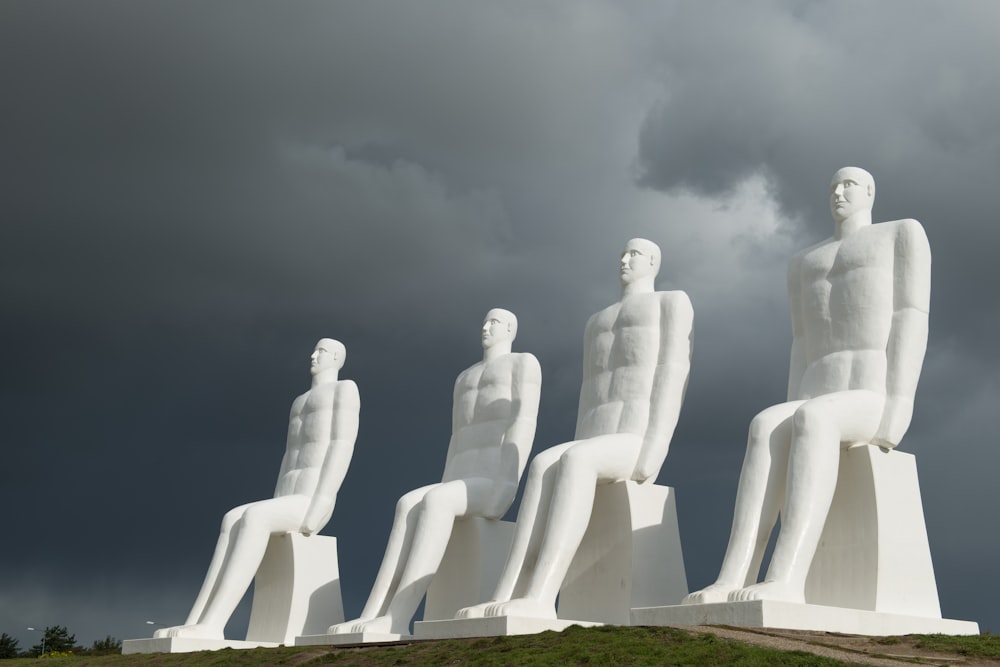 un grupo de estatuas blancas sentadas en la cima de un exuberante campo verde