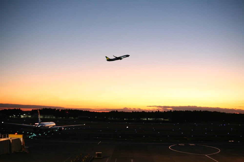 an airplane is flying in the sky at sunset