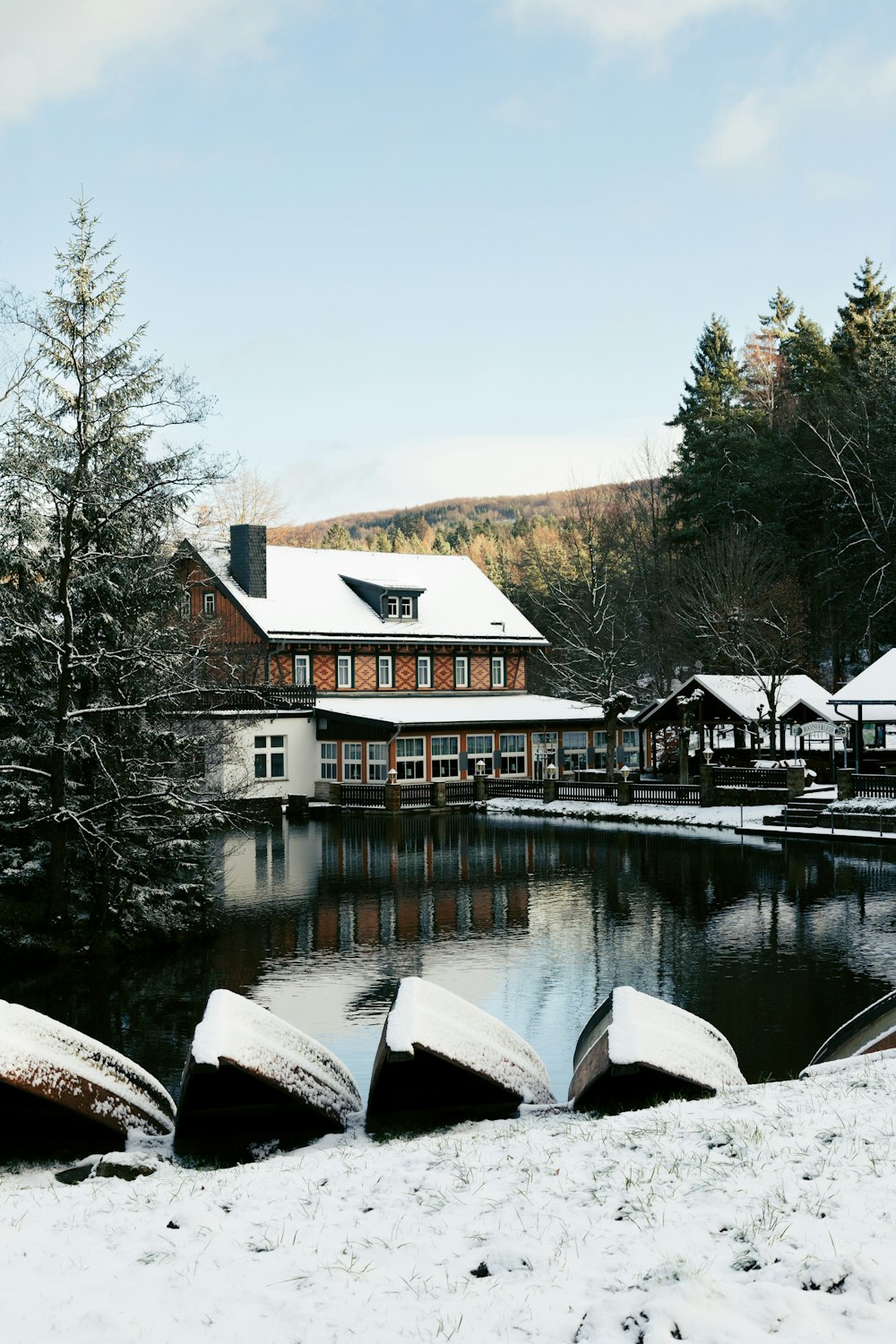 a lake surrounded by snow covered trees next to a building