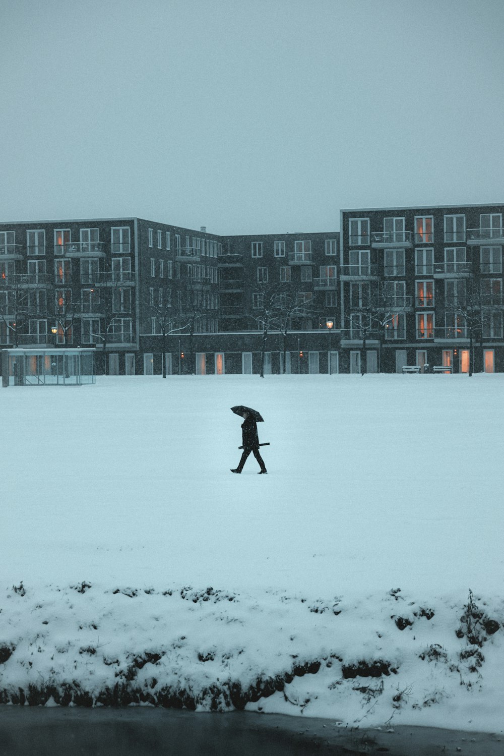 eine Person, die mit einem Regenschirm im Schnee spazieren geht