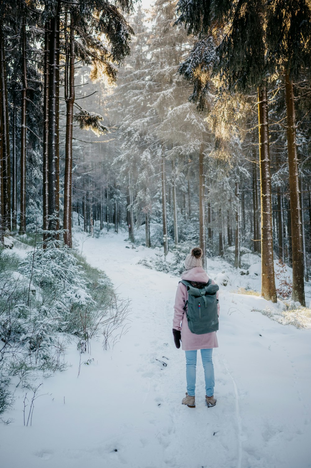 Uma mulher de casaco rosa está andando pela neve