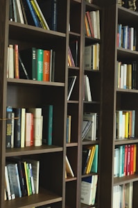 a bookshelf filled with lots of books on top of a hard wood floor