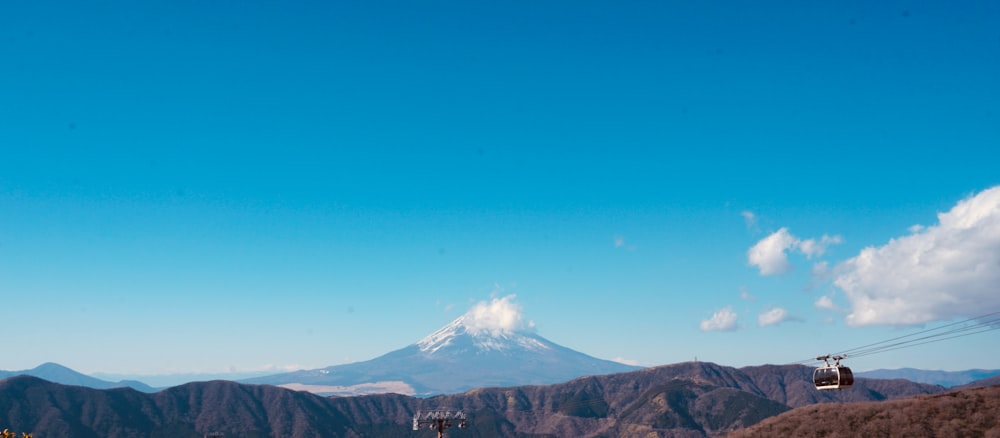 a ski lift going up a mountain with a mountain in the background