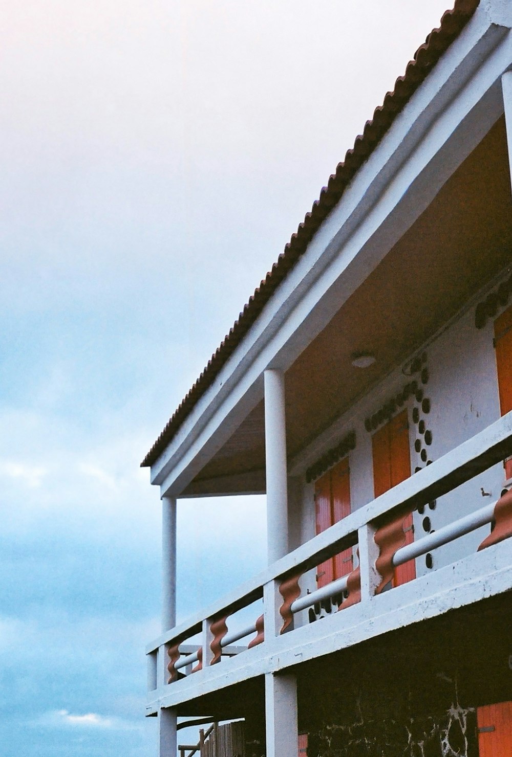 a white building with red shutters and a balcony