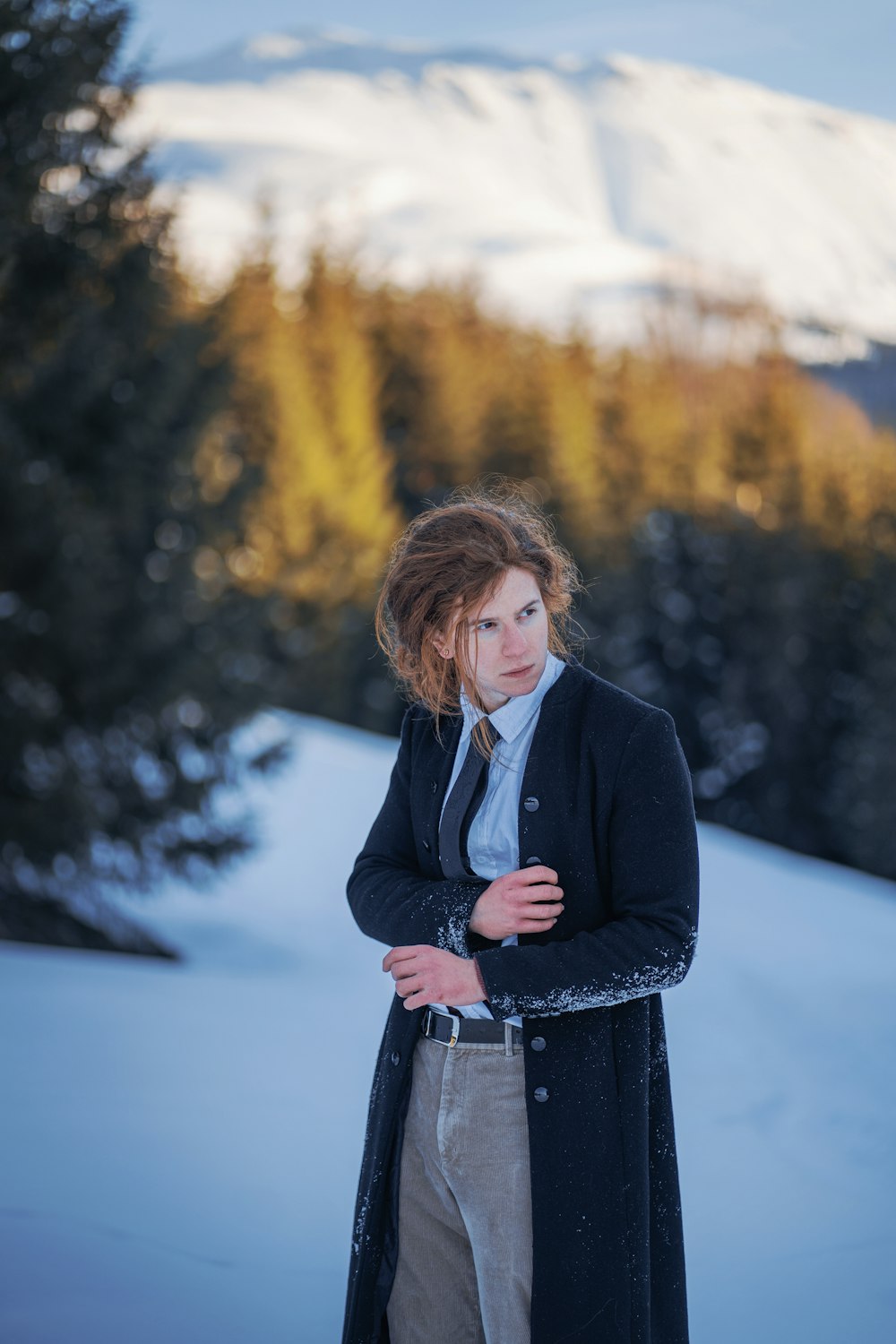 a woman standing in the snow with a mountain in the background