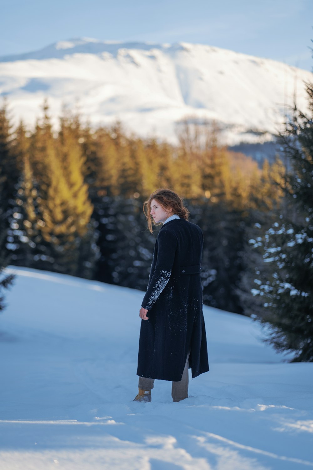 a woman standing in the snow with a mountain in the background