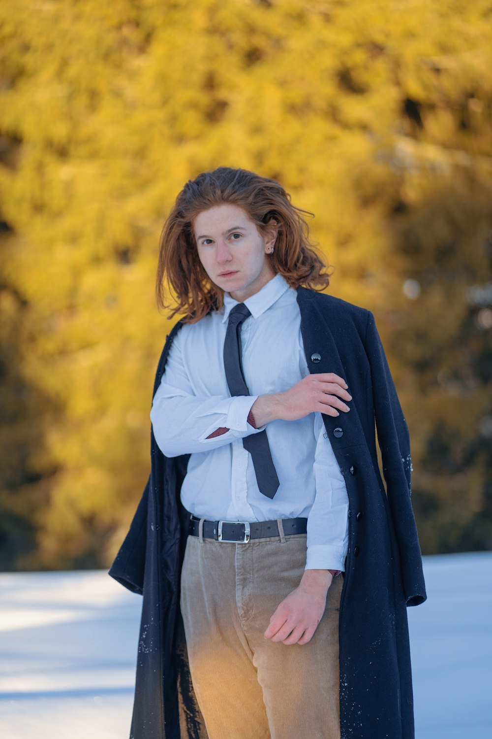 a woman wearing a coat and tie standing in the snow