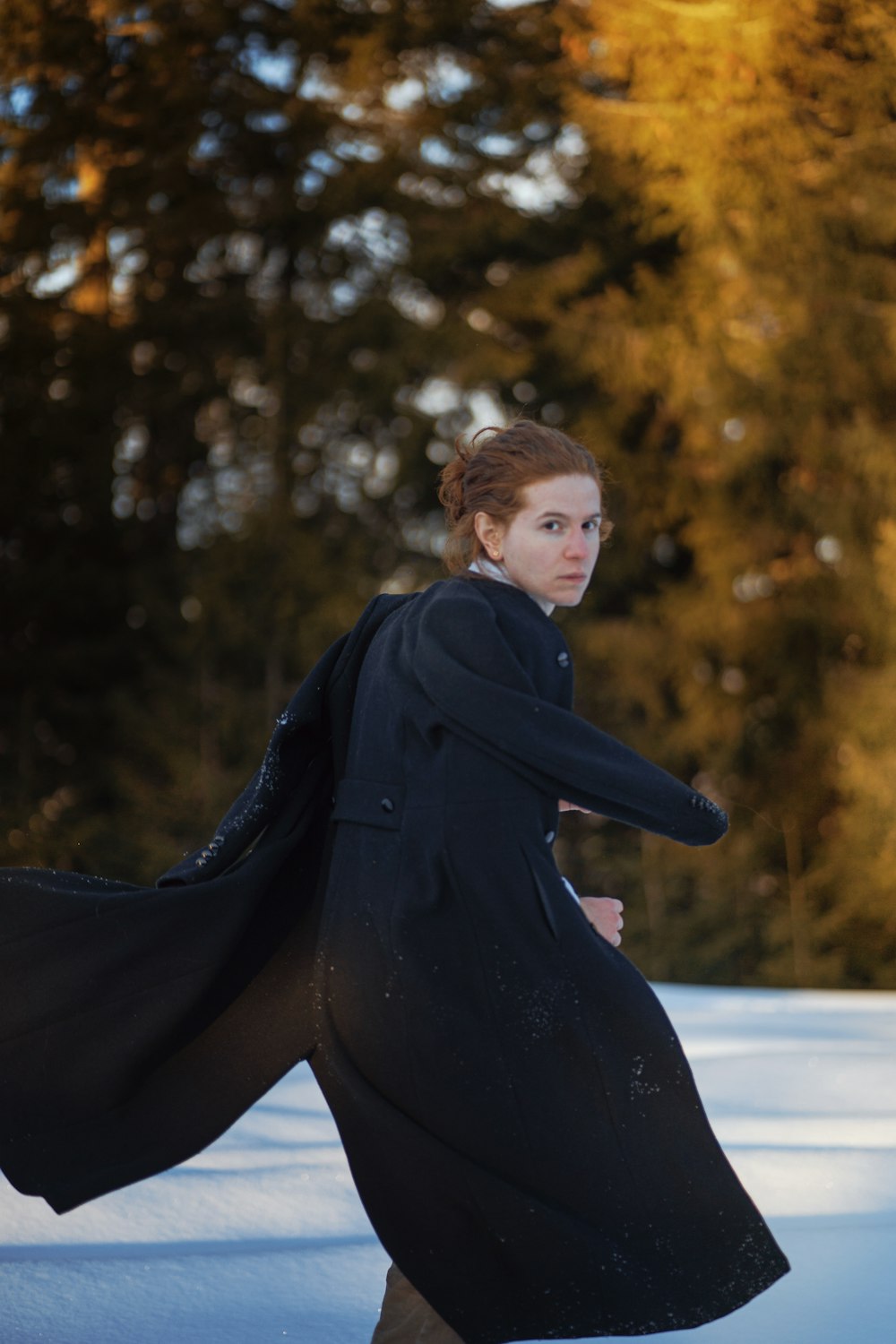 a woman in a black coat is walking in the snow