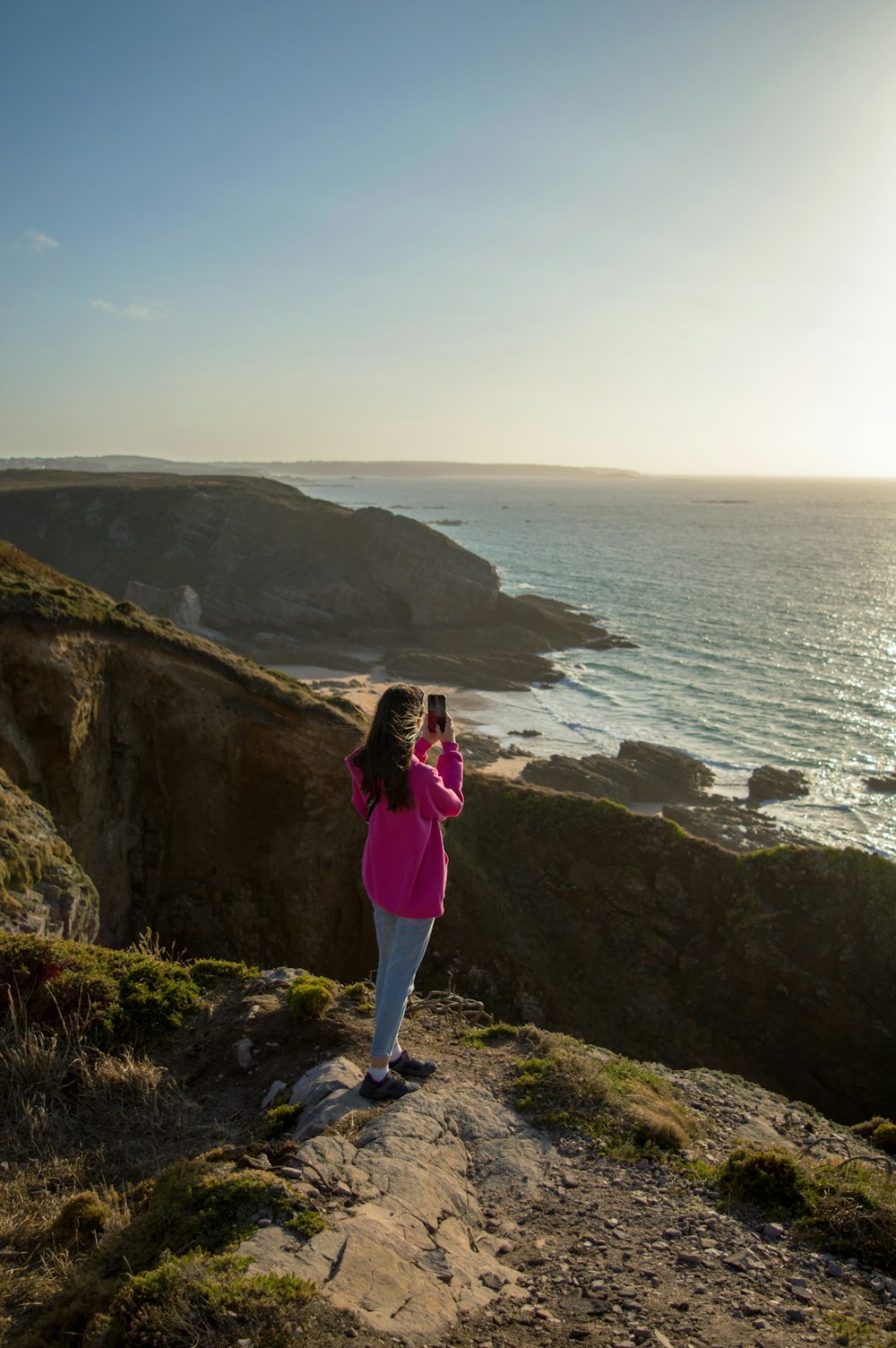 Une femme prenant une photo de l’océan avec son téléphone portable