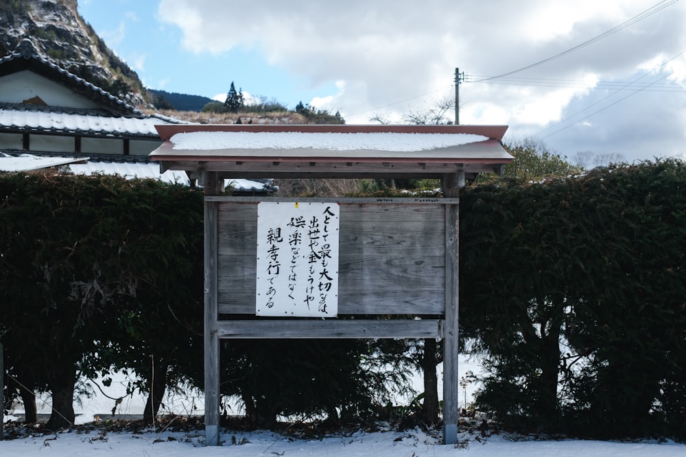 a wooden sign sitting in front of a snow covered field