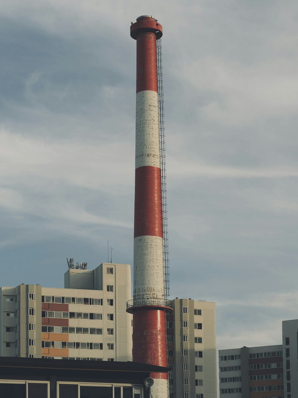 a tall red and white tower next to a tall building