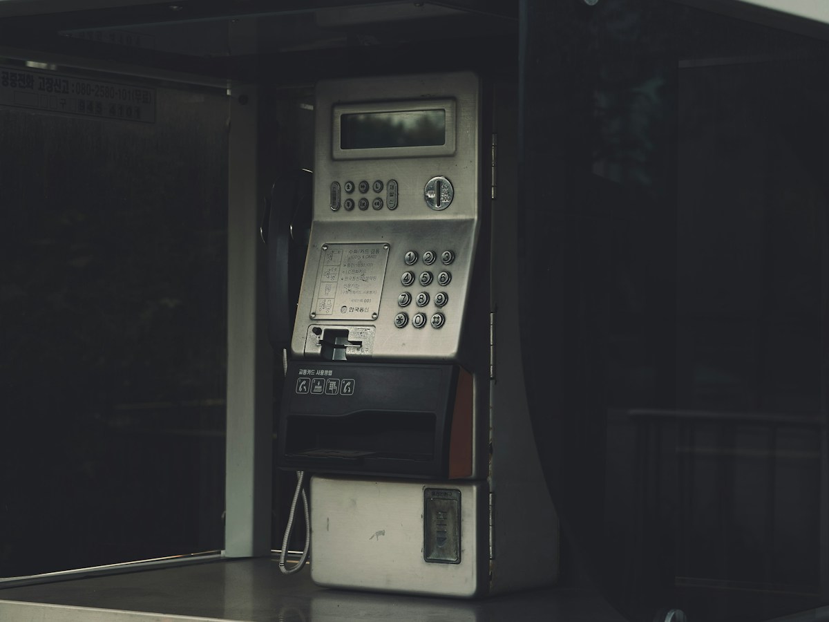 A pay phone on a concession stand counter with snacks and drinks in the background.