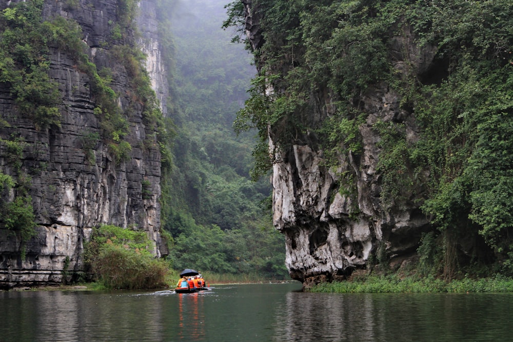 a person in a boat on a river surrounded by mountains