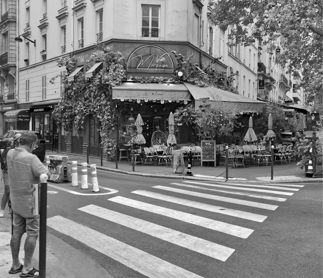 a black and white photo of a street corner, La façade « fleurie » de ce restaurant enlumine ce coin de rue de la capital