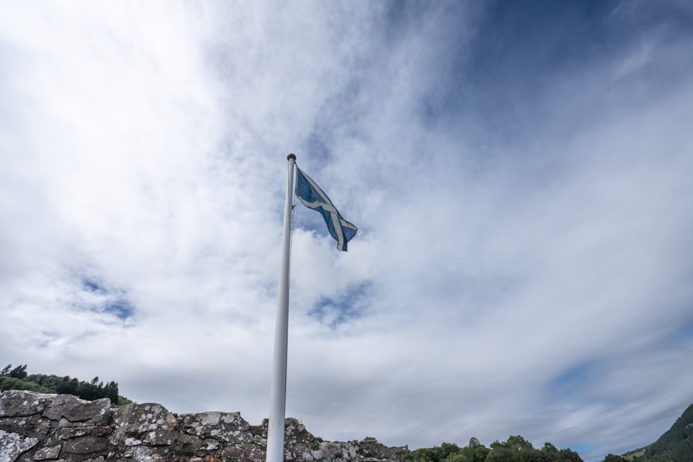a flag flying high in the sky next to a stone wall