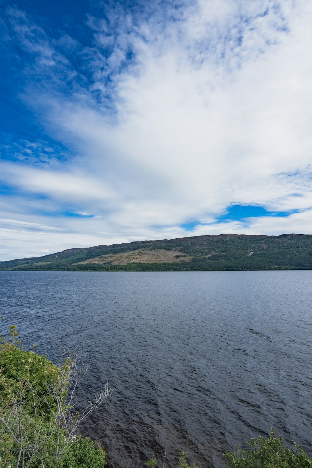 a large body of water surrounded by a lush green hillside