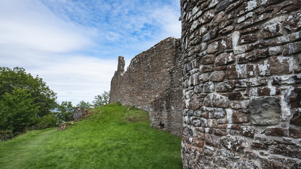 a stone wall with grass growing on the side of it