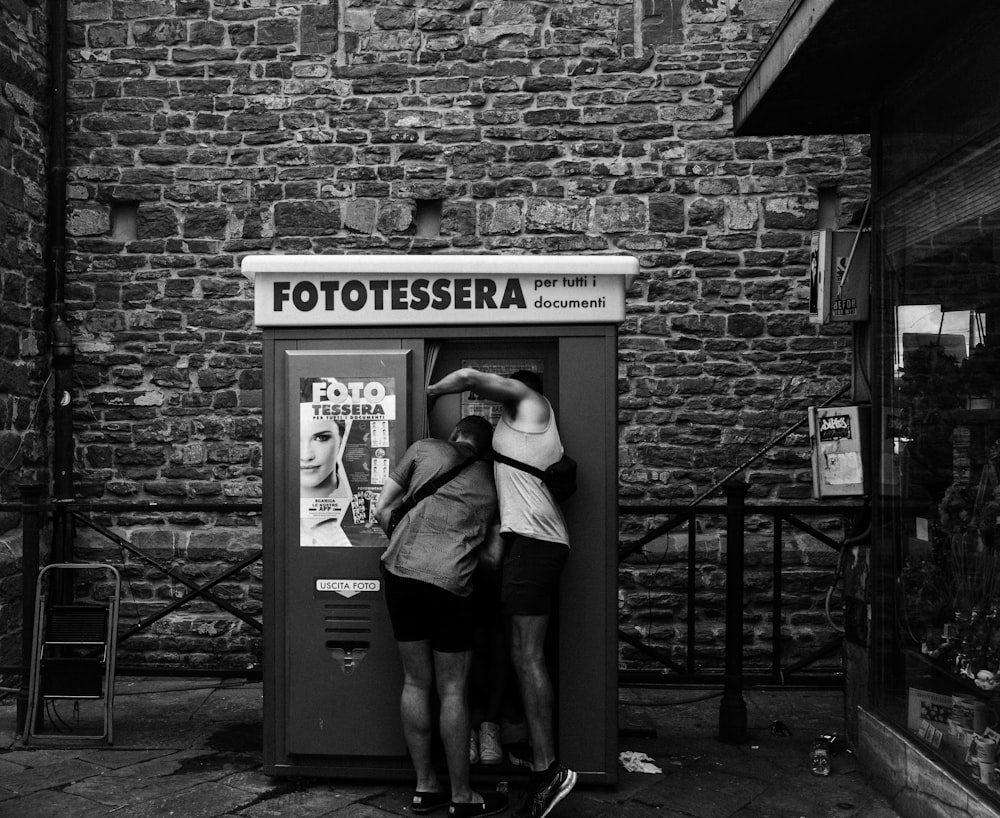 a couple of people that are standing in front of a phone booth